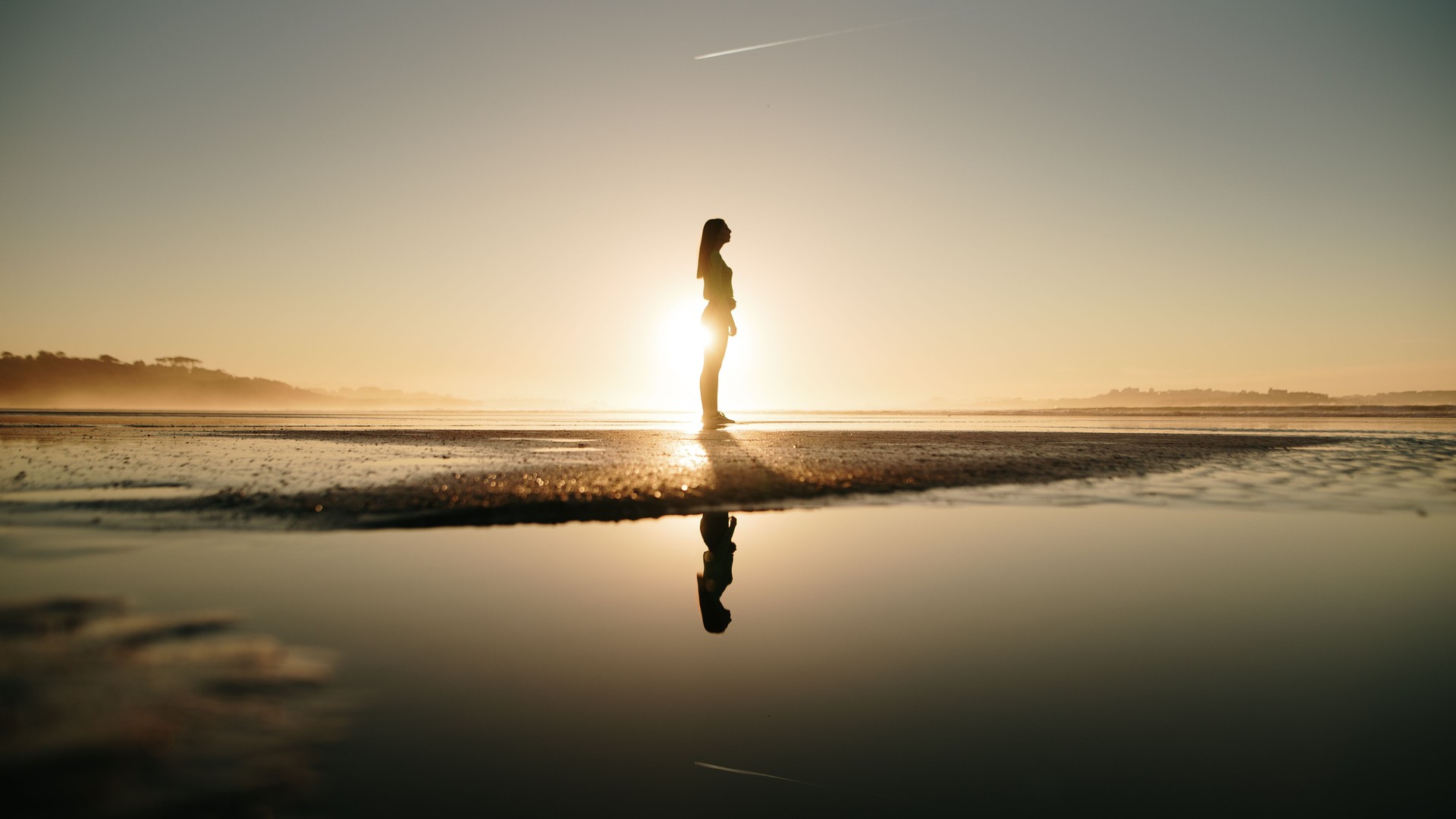 Young woman at beach at sunset and her reflection