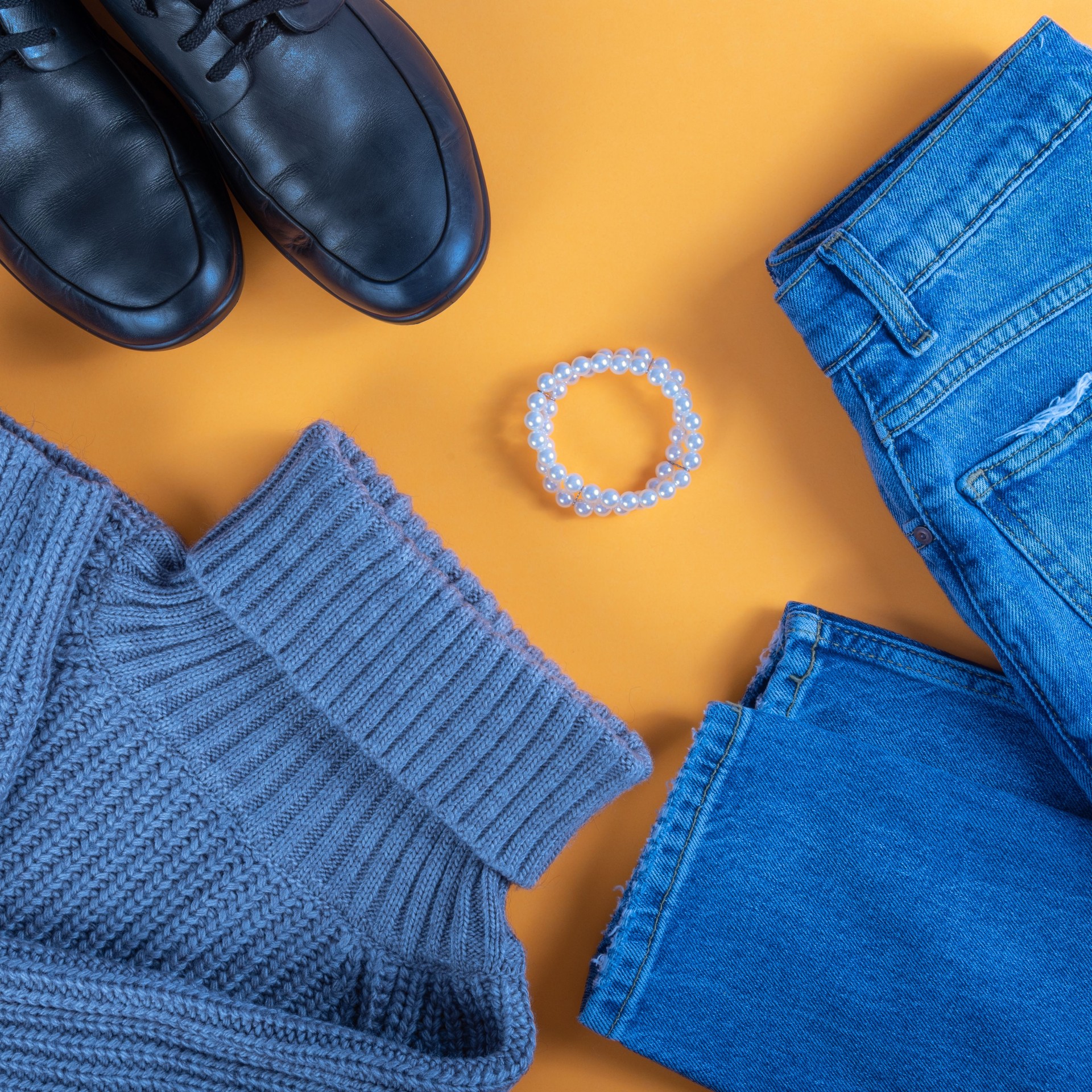 Casual wear set - Layout on a flat lay. Jeans, sweater and boots on a yellow background